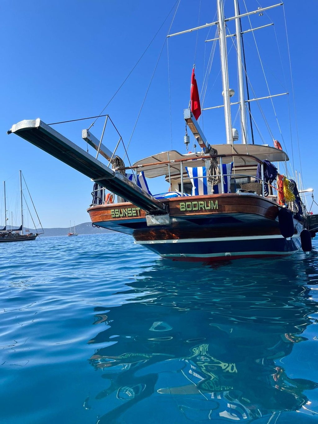 Mavi suda, arka kısmı ve Türk bayrağı görünen gulet yat.