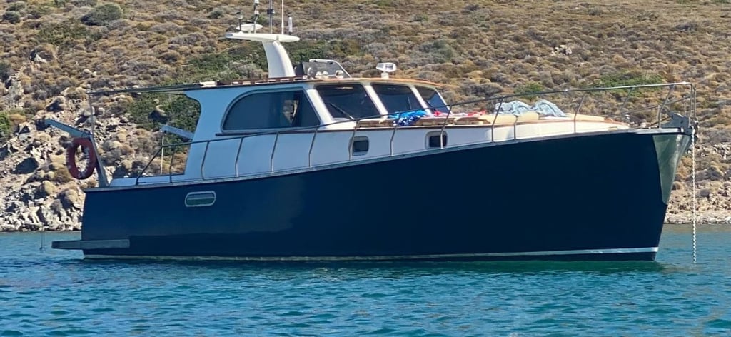 Mavi suda, kayalık kıyıya yakın koyu renkli motor yat.