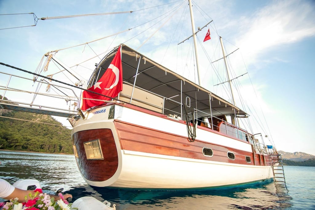 Denizde, Türk bayrağı asılı ahşap ve beyaz renkli yelkenli tekne.
