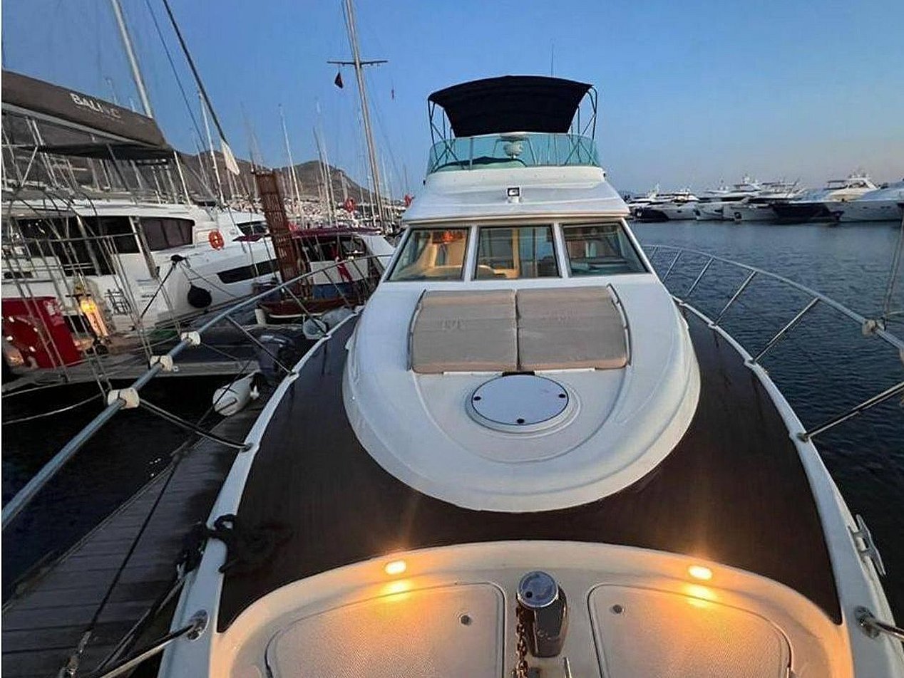 Marinada, siyah ve beyaz renkli, üstü açık güvertesi olan motor yat.