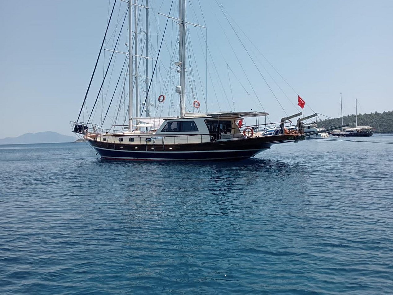 Mavi denizde, yelken direkleri ve Türk bayrağı olan gulet tipi yelkenli tekne.