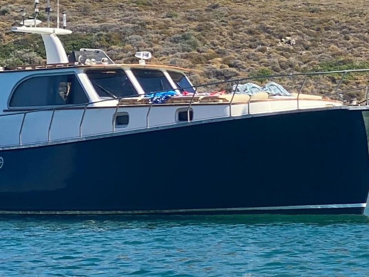 Mavi suda, kayalık kıyıya yakın koyu renkli motor yat.